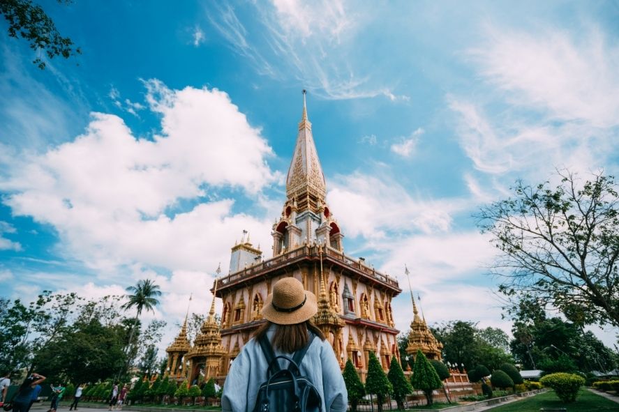 traveler exploring a temple in phuket under a bright blue sky